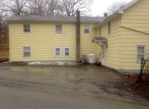 the outside of a yellow house with a parking lot