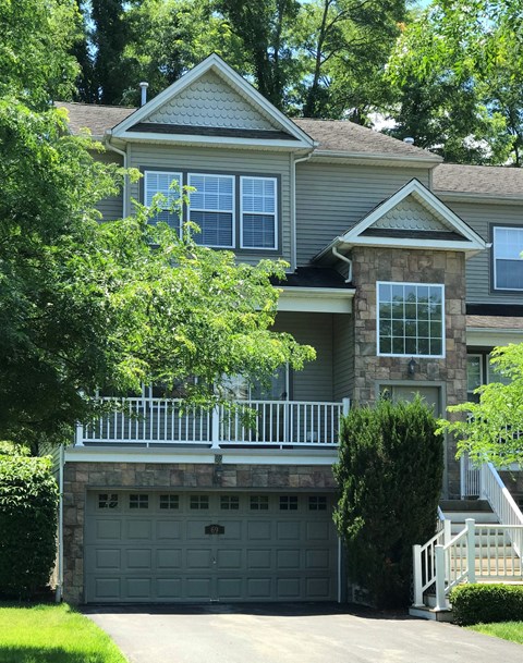 A house with a grey garage door and a white fence.