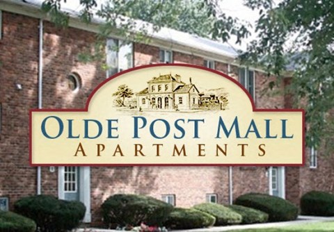 a sign for old post mall apartments in front of a brick building