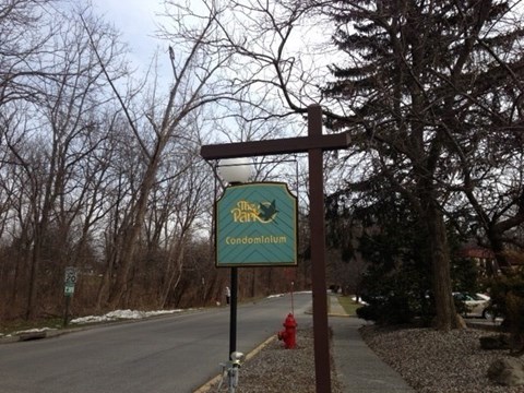 A sign for The Park condominium is displayed on a post.