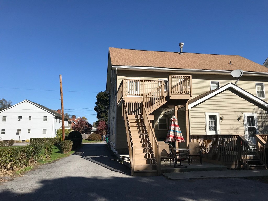 the back of the house with an outdoor deck and an umbrella
