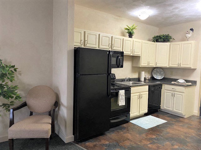 a small kitchen with a black refrigerator and a chair