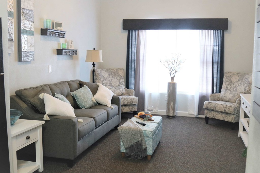 a living room with a couch and chairs and a window
