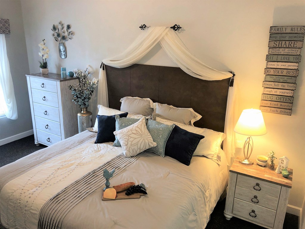 a bedroom with a bed with a white comforter and pillows