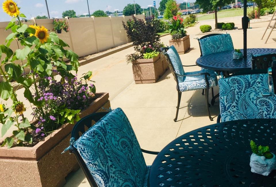 a patio with blue chairs and tables and flowers