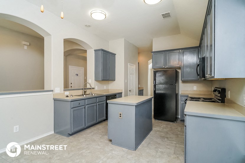 a kitchen with blue cabinets and a black refrigerator