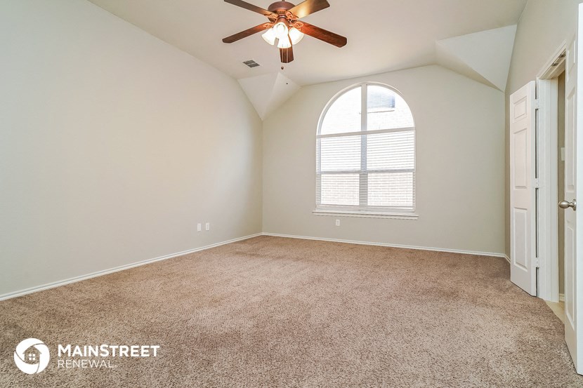 the master bedroom has a large window and carpeted flooring