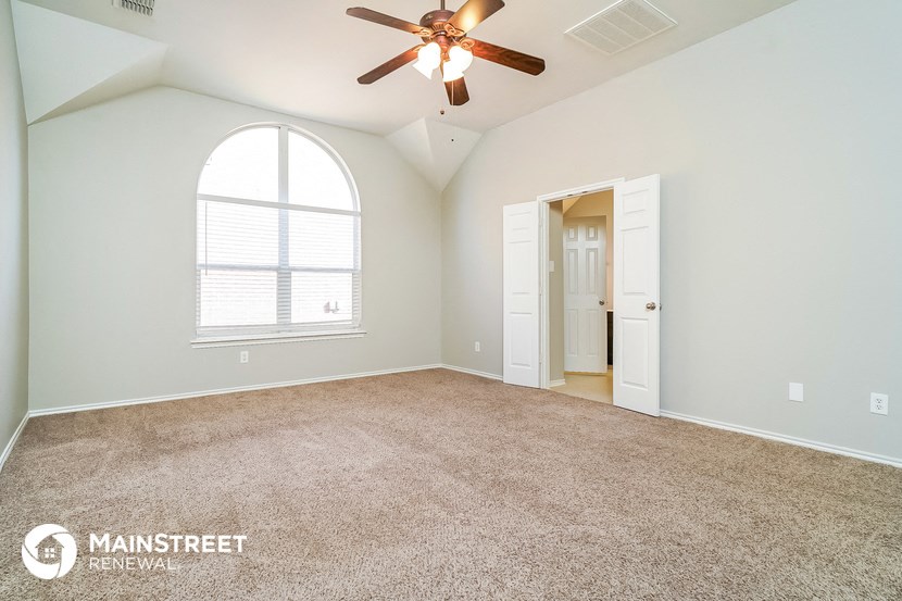 the master bedroom has a large window and carpeted flooring