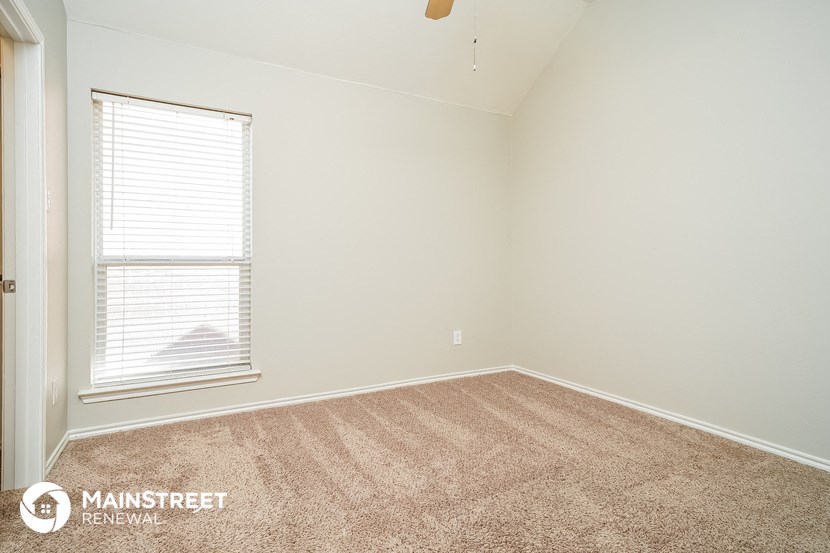 a bedroom with a window and a carpeted floor