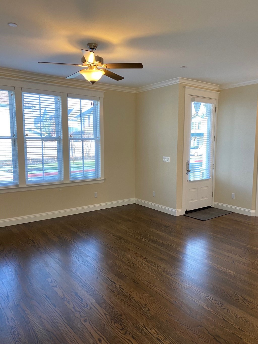 an empty living room with wooden floors and a ceiling fan