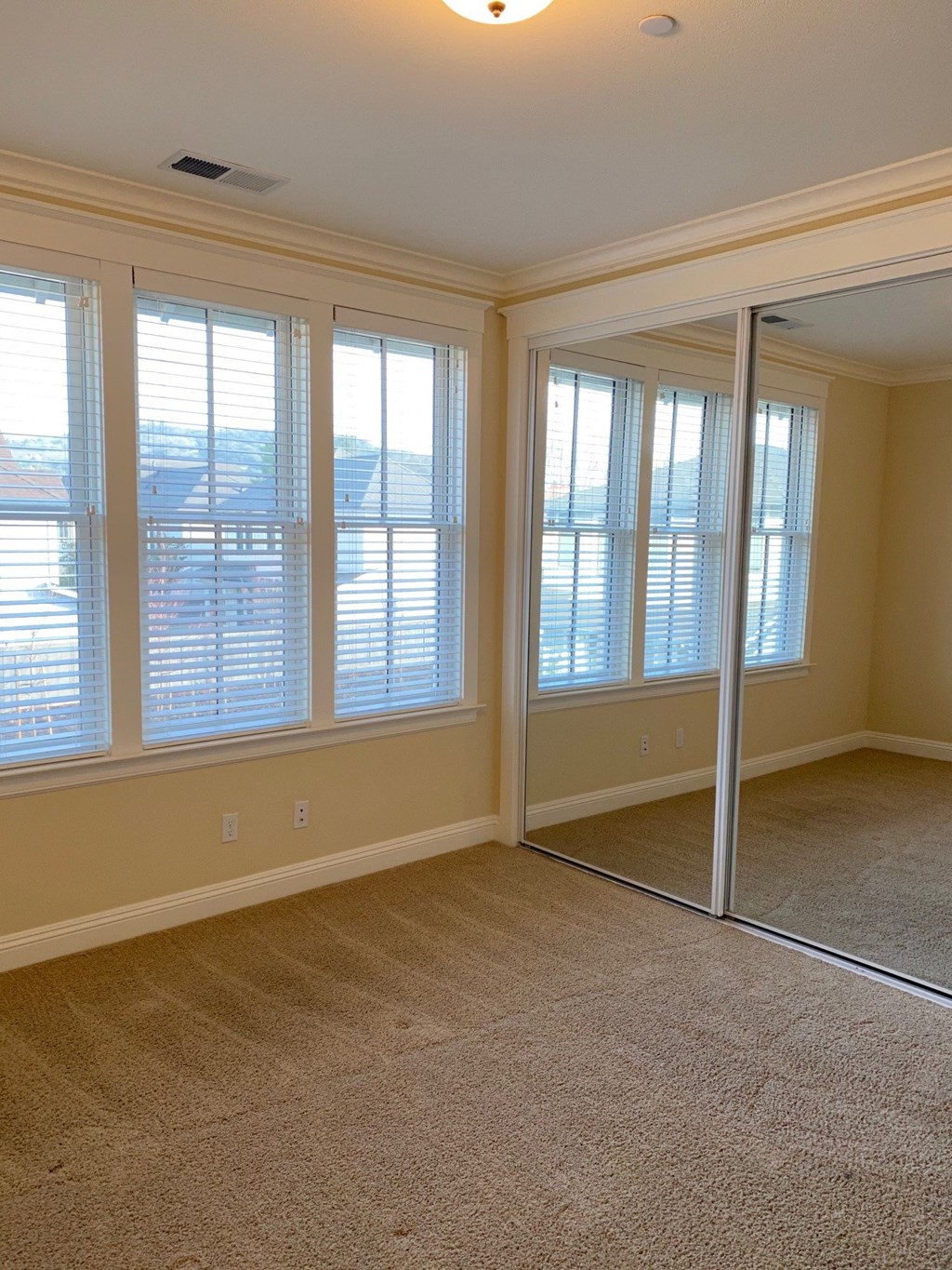 an empty living room with windows and a mirror