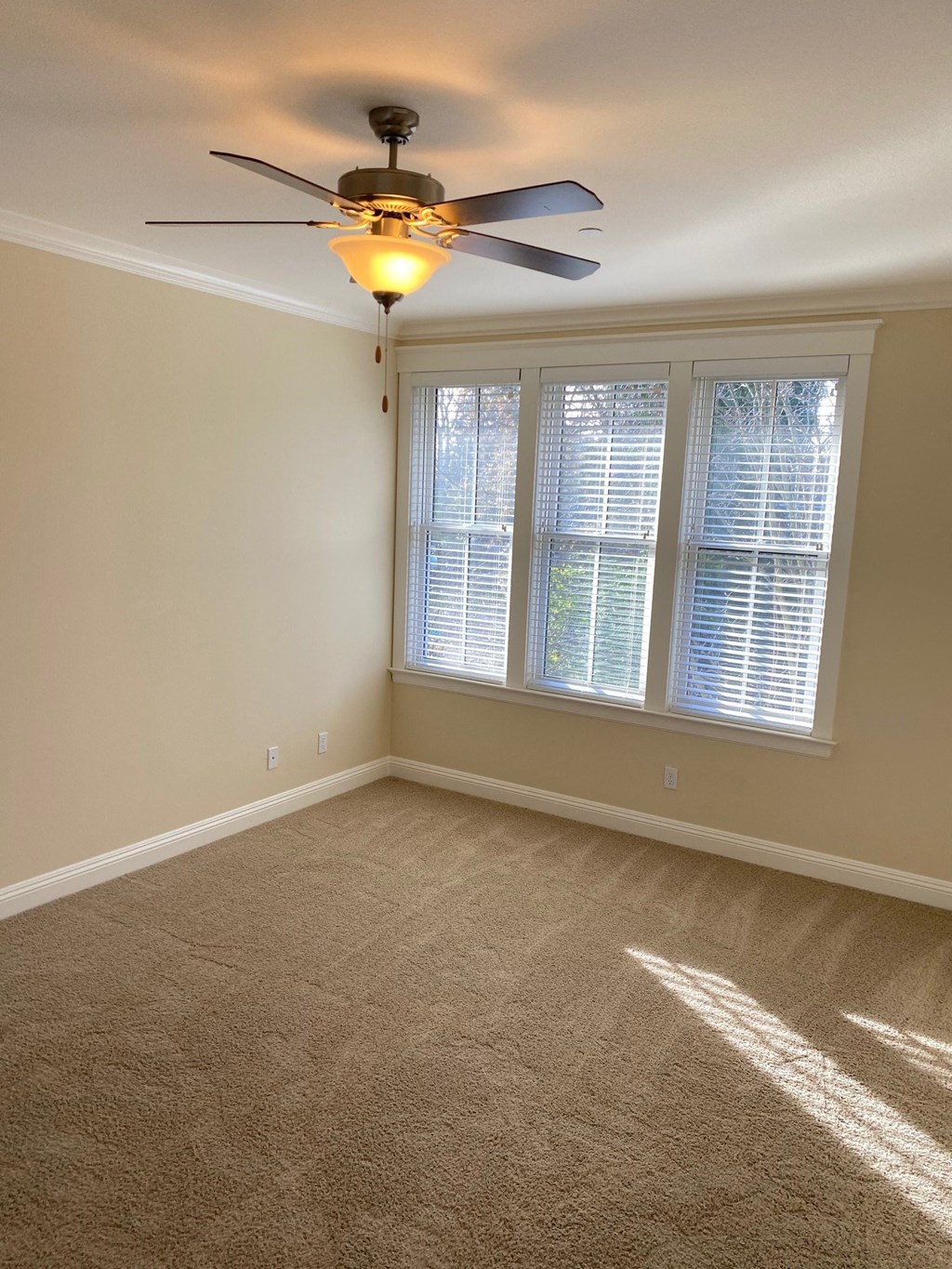 an empty living room with a ceiling fan and a window