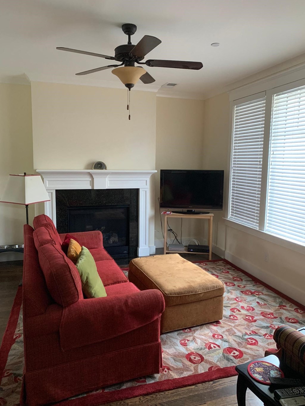 a living room with a red couch and a ceiling fan