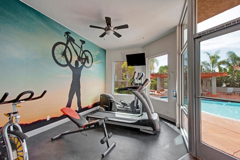 a gym with a bike mural on the wall and a pool