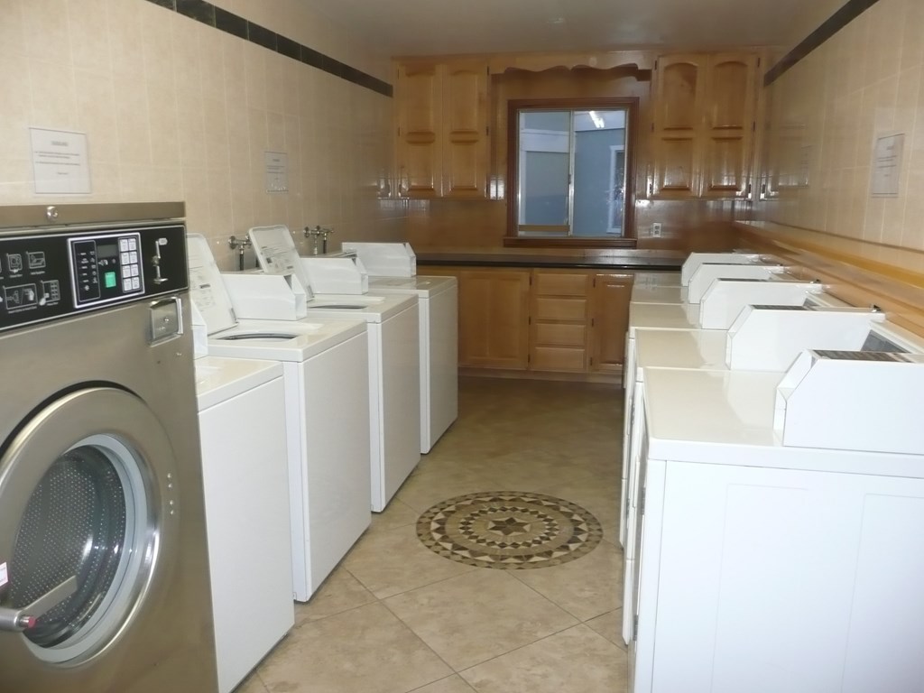 a laundry room with a row of washers and dryers