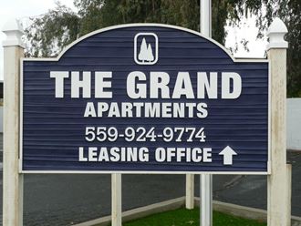 a blue sign that reads the grand apartments leasing office