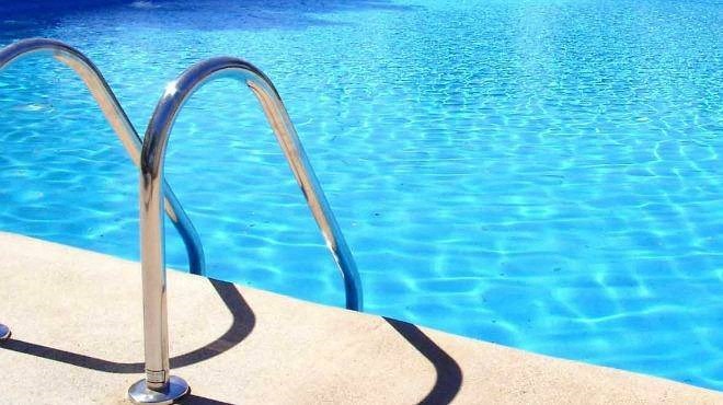 a stainless steel hand rail next to a swimming pool