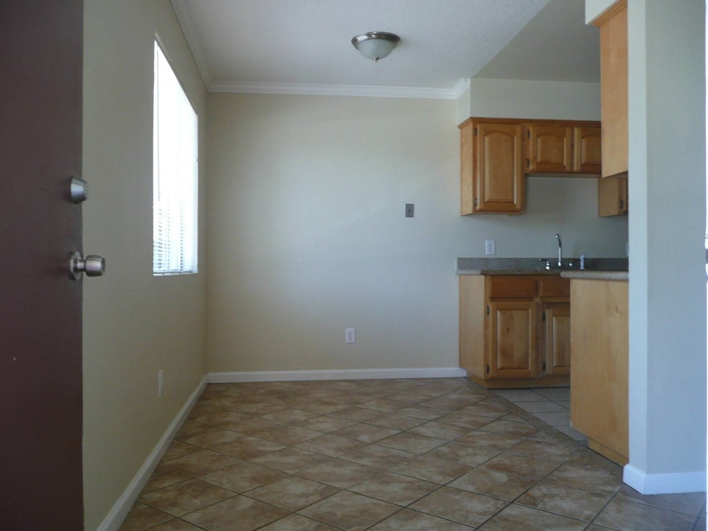 an empty kitchen with wooden cabinets and tile flooring
