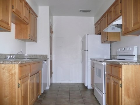 an empty kitchen with wooden cabinets and a white refrigerator