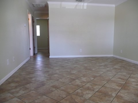 an empty living room with tile flooring and white walls