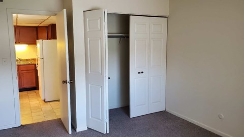 A kitchen with a refrigerator and a pantry with a door open.