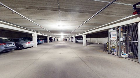 A long, empty parking garage with cars parked on the left side.