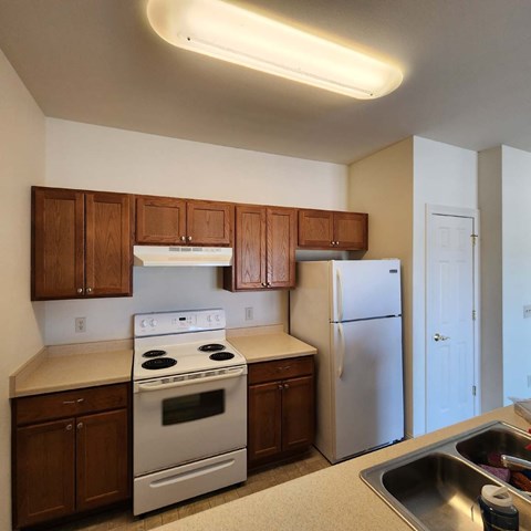 A kitchen with white appliances and wooden cabinets.