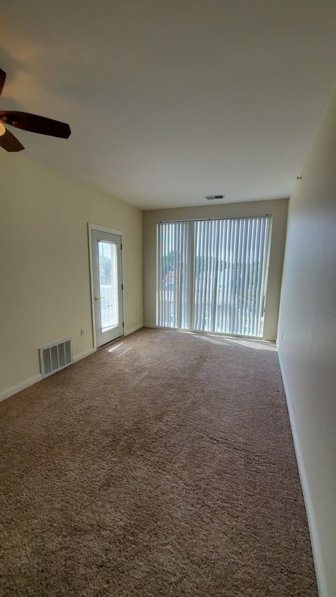 A room with a carpeted floor and a ceiling fan.