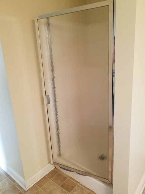 A shower stall with a glass door is in a bathroom.