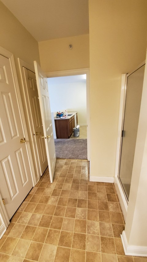 A hallway with a brown tiled floor and white walls.