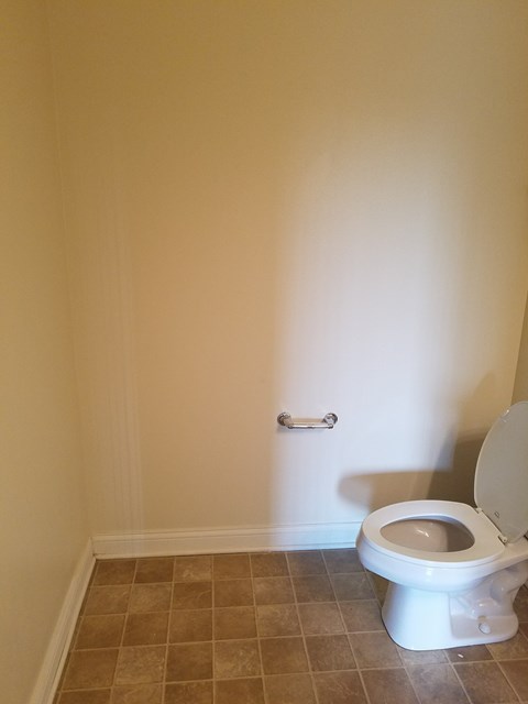 A white toilet in a bathroom with beige tiles.
