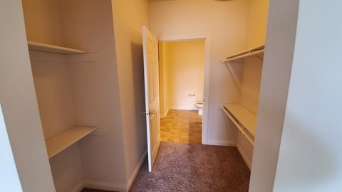 A hallway with a carpeted floor and white walls.