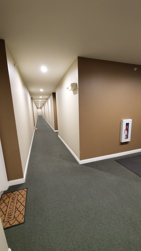A hallway with a carpeted floor and a "Welcome" doormat.