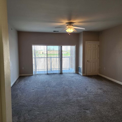A room with a ceiling fan and carpeted floor.