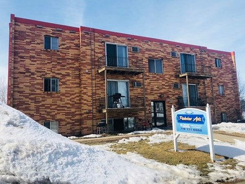 A building with a sign in front that says "Faber Apartments" and a phone number.