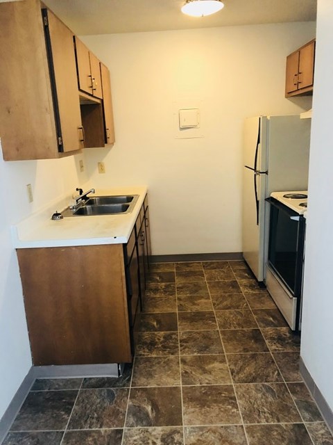 A kitchen with brown cabinets and a tiled floor.