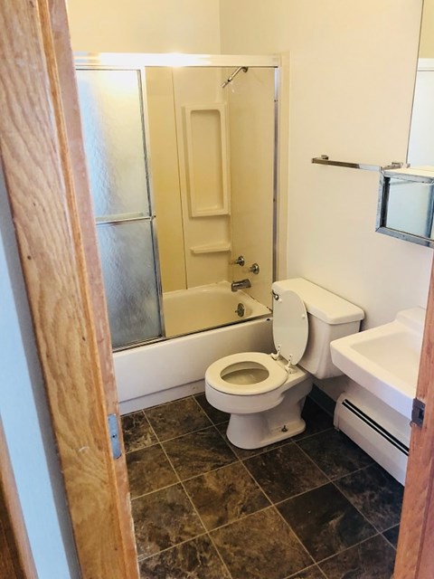 A white toilet is in a bathroom with a walk-in shower.
