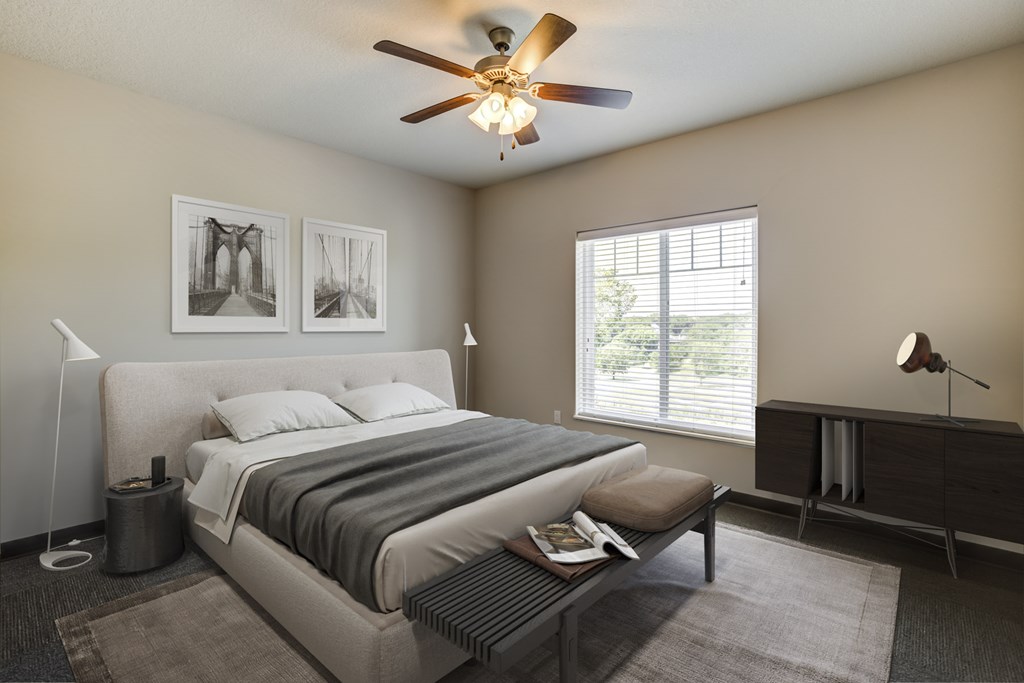 Fairway Flats Bedroom with Stylish Decor, Luxury Vinyl Flooring, Large Window, Beige Walls, and a Ceiling Fan