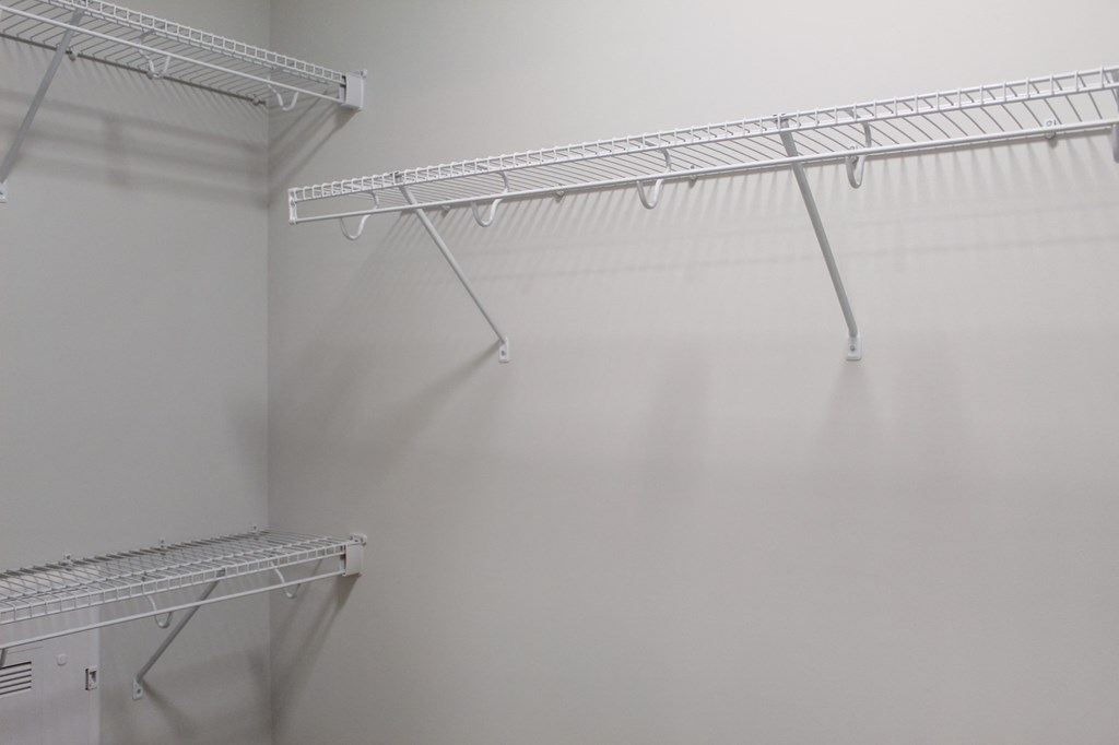 a walk in closet with white walls and white shelves and racks on the wall