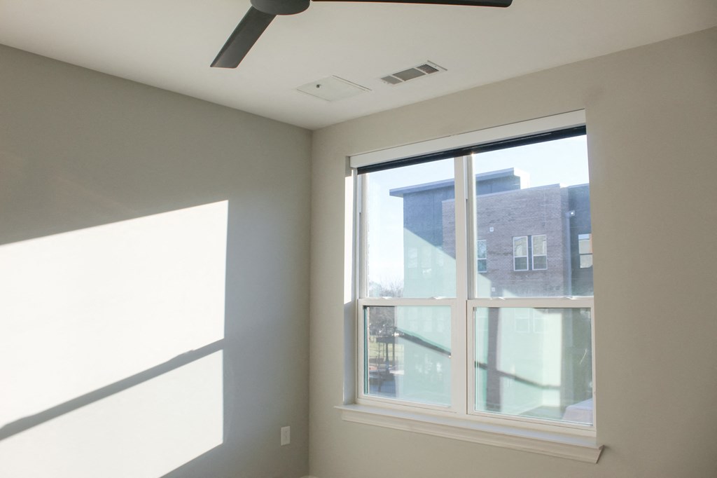 a bedroom with a large window and a ceiling fan