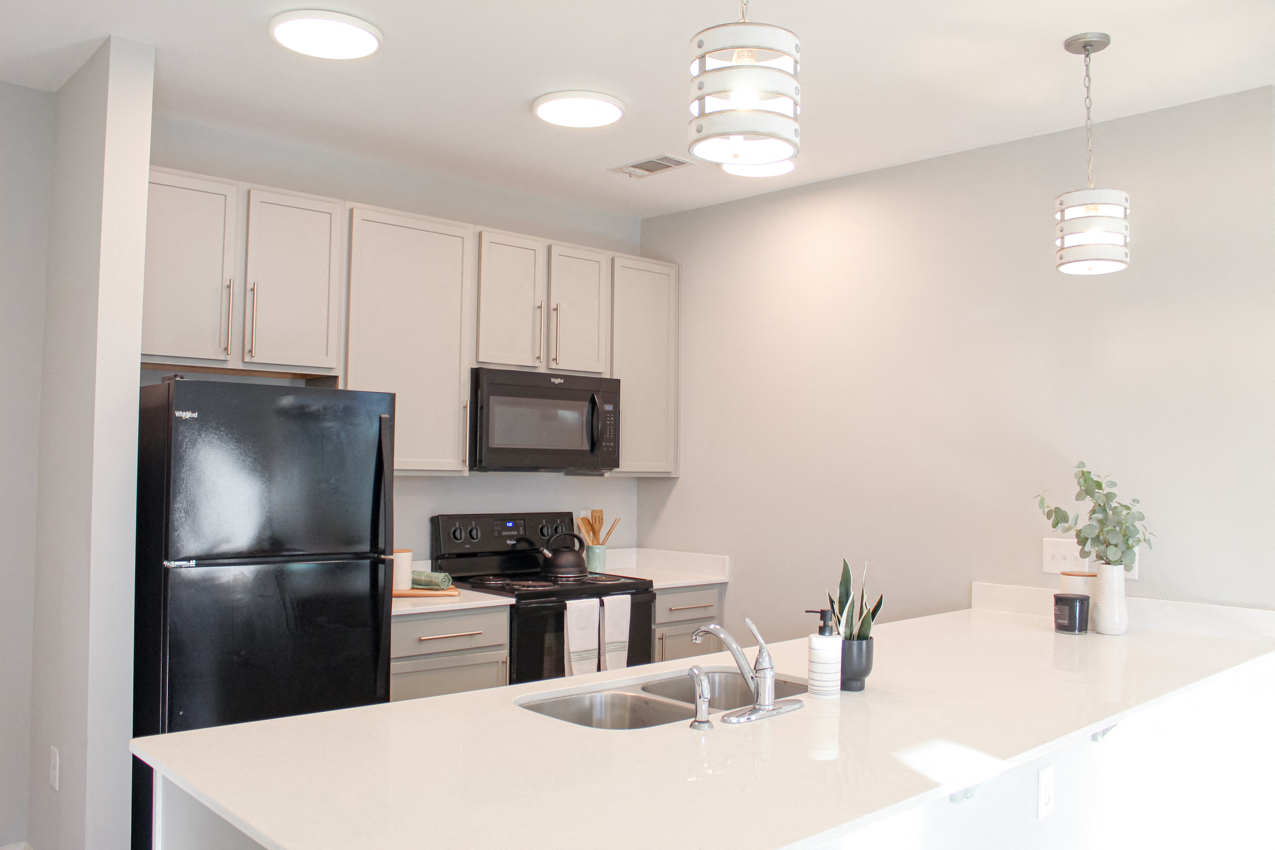a white kitchen with black appliances and white counter tops