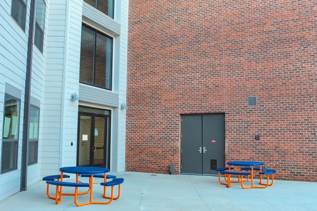 a courtyard with tables and chairs in front of a brick building