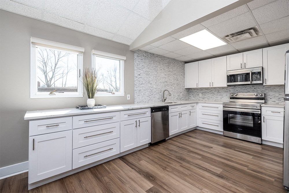 an empty kitchen with white cabinets and stainless steel appliances