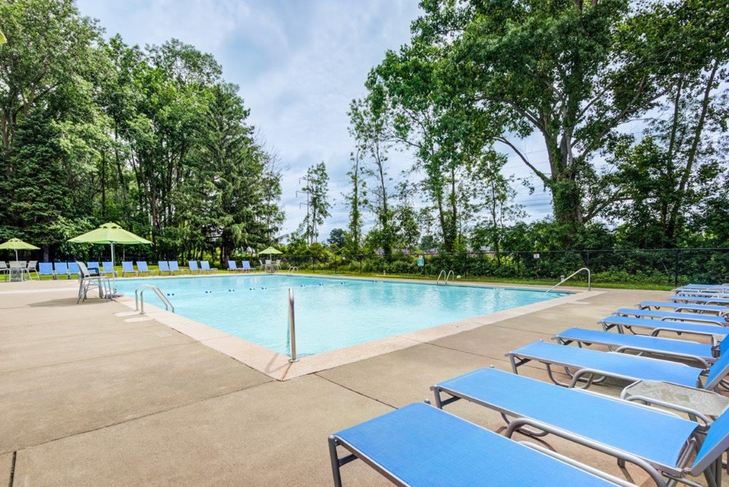 a resort style swimming pool with blue lounge chairs and trees