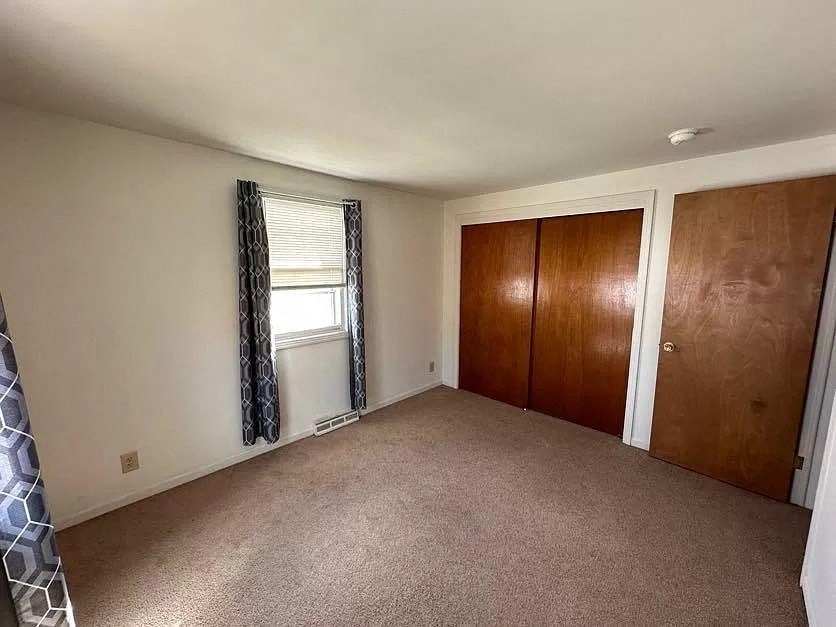 an empty room with a closet and a window