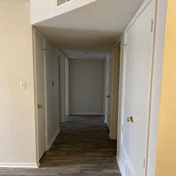A hallway with white doors and a wooden floor.