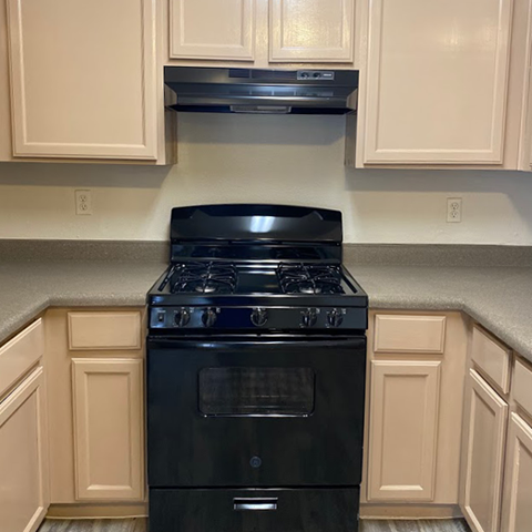 A black stove top oven in a kitchen with beige cabinets.