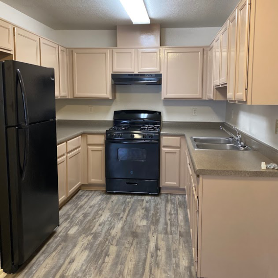 A kitchen with a black fridge and black oven.