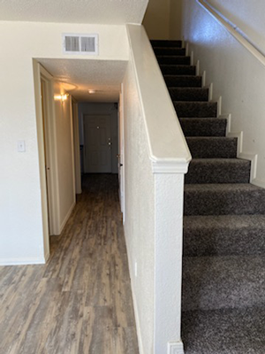 the hallway of a house with stairs and a carpeted floor