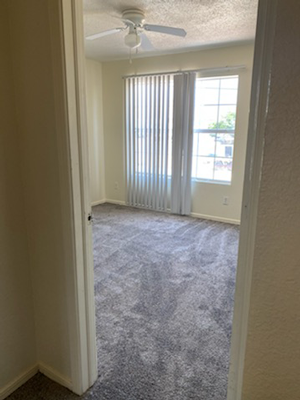 an empty living room with a window and a ceiling fan